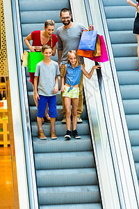 家庭在购物商场用自动扶梯带袋子的扶梯店铺妈妈幸福夫妻兄弟姐妹母亲男生购物袋男人中心图片