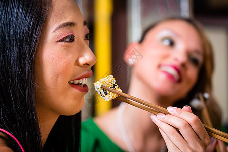 亚洲餐馆的年轻人吃寿司 青年餐厅女性女士菜肴筷子午餐盘子用餐朋友们食物图片