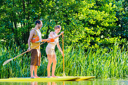 在河上站起手掌板的女人运动装旅行运动闲暇乐趣划桨木板桨板夹克生活图片