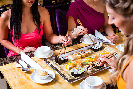 亚洲餐馆的年轻人吃寿司 青年食物菜肴女性用餐盘子餐厅午餐女士朋友们筷子图片