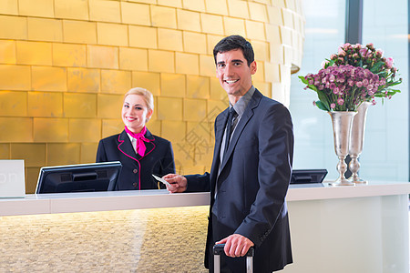 提供钥匙卡的男子在旅馆接待员检查客人职业商业女士男人商务卡片接待桌子前台图片