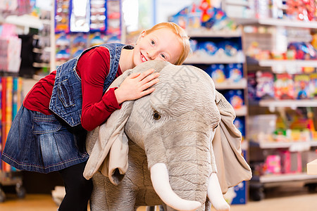 玩具店的小女孩和充装动物抱在一起孩子店铺女儿零售玩具毛绒女孩购物填充图片