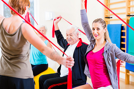 在健身体育馆参加健身课的老年人医疗康复体操物理疗法女士运动健康橡皮筋男人图片