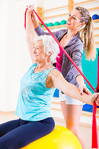 健身时带伸展带的高级妇女康复培训师橡胶橡皮筋教练理疗师健身房治疗锻炼疗法图片