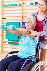 坐在轮椅上做理疗的高级妇女体操培训师工作室物理治疗疗法医疗训练老年人康复图片