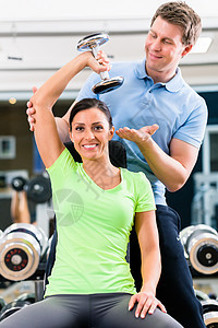 体育锻炼中的年轻女性和教练员哑铃锻炼培训师活动女士运动俱乐部健身私人男人图片