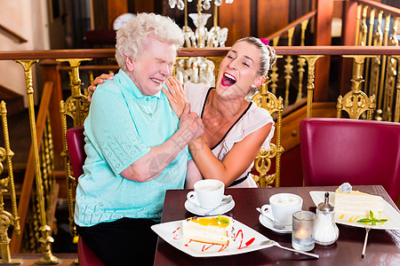 外婆和孙女在咖啡馆大笑拥抱杯子祖母咖啡家庭吊灯老年乐趣女儿蛋糕图片