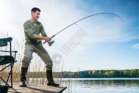渔夫在湖边钓鱼男人闲暇娱乐钓竿垂钓者牵引运动码头爱好图片