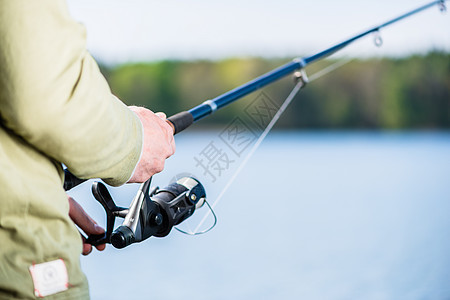 人类在湖边以角钓鱼娱乐闲暇渔夫男人垂钓者爱好钓竿运动图片