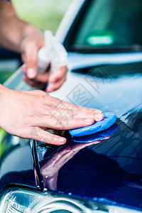 在自动洗涤时给蓝色汽车打蜡的男性手贴紧海绵反射物质男人服务打扫工作圆形喷雾器员工图片