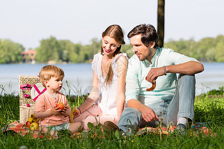 家庭在湖边野餐 坐在草地上男生食物父母孩子爸爸女士毯子儿子妈妈微笑图片