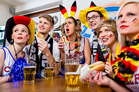 足球球迷观看德国国家队的一场比赛旗帜团体酒吧风扇锦标赛播送体育配件啤酒餐厅背景图片