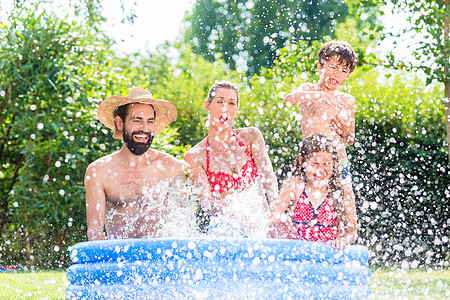泼水的素材家庭冷却下来 在花园池中泼水闲暇水池乐趣男人父亲热浪娱乐幸福女士孩子们背景