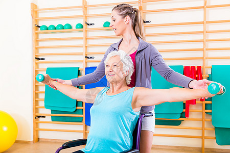 坐在轮椅上做理疗的高级妇女健身房体操运动哑铃疗法医疗康复训练教练物理图片