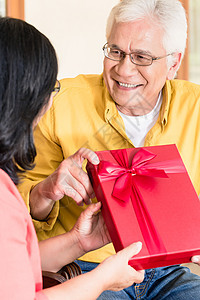 相爱的亚洲老年情侣在拿着礼物时微笑着笑容图片