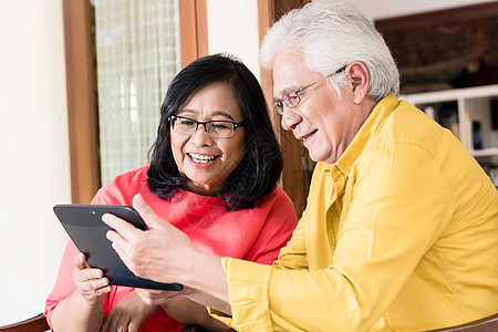 相爱的亚洲老年情侣在拿着平板纸时微笑着笑容图片