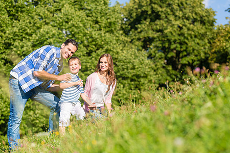 家庭坐在草地上 儿童挥手妻子乐趣公园爸爸树木天空男生快乐母亲太阳图片