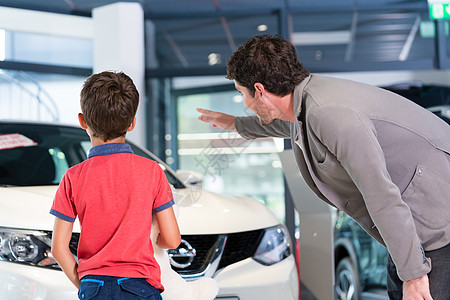 父亲和儿子在汽车经销商展厅买车男人孩子们顾客后代男生家用车陈列室爸爸代理商图片