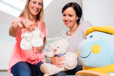 孕妇及其朋友为婴儿准备育婴幼儿的托儿所怀孕母亲女性微笑孩子父母儿童婴儿房朋友们靴子图片