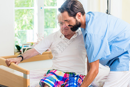 老年护理护士帮助老年人从轮椅到床上睡觉男人退休照顾者职员医院病人医学诊所病床祖父图片