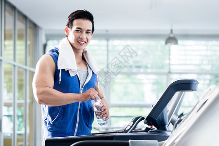 在运动车装水瓶上微笑的年轻人耐力瓶子俱乐部课程肌肉机器跑步机训练跑步健身图片