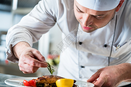 厨师把食物放在盘子上装饰 以完成菜盘图片