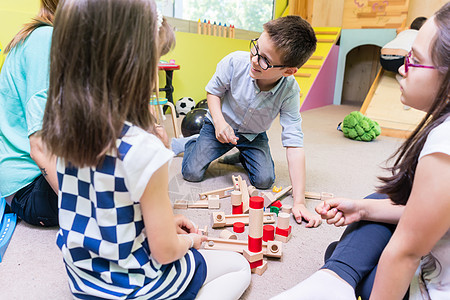 学龄前男孩在幼儿园老师的指导下与孩子们合作地面时间课堂玩具学前班男生女士女性教育积木图片