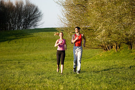为户外运动而慢跑的情侣草地活动娱乐训练运动闲暇乐趣成人夫妻阳光图片