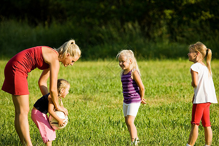 家庭踢足球乐趣公园阳光后代游戏童年女儿女儿们活动草地图片