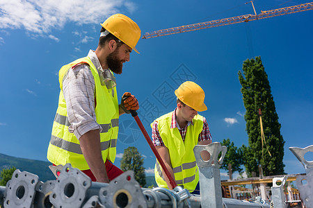 两名效率高的蓝领雇员建造一个金属脚手架员工背心建筑工作职业同事建设团队劳动者耐用性图片