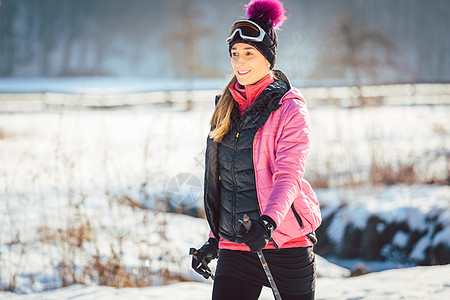 女子在冬季远足的征途上运动健走晴天踪迹帽子衣服手杖棍子图片