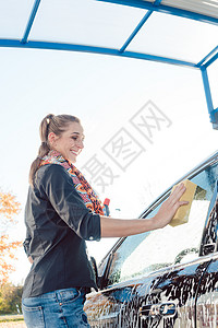 女性在她的汽车上泡泡泡沫喷嘴刷子自助软管压力洗涤商业打扫洗涤剂服务图片
