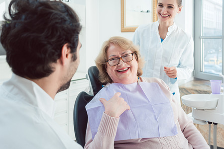 牙科医生和助理请高级病人贺卡职业团队护理人员治疗白色牙齿牙医手术房间老年图片