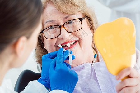 显示高级病人牙齿颜色样本的牙科医生同事护士预防护理人员诊所医生老年职业手术团队图片