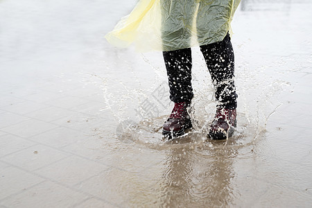 女人在雨中玩耍 在水坑里跳跑步行动运动城市沥青女士天气训练飞溅闲暇图片
