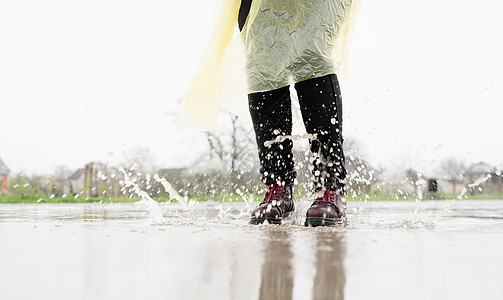 女人在雨中玩耍 在水坑里跳训练运动活力城市女孩沥青乐趣闲暇速度天气图片