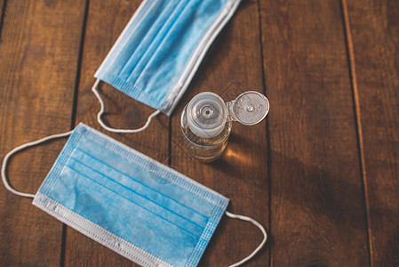 洗手液和一次性面罩放在木制桌子上手术药品液体防护卫生口罩消毒剂凝胶乙醇消毒预防图片