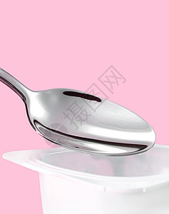粉红背景的酸果杯和银勺 含酸奶霜的白色塑料容器 用于健康饮食和营养平衡的新鲜奶制品乳糖牛奶早餐杯子营养饮食勺子产品小吃食物图片