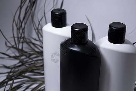 由三个白色和黑色洗发水瓶组成 在干叶附近没有标签 身体护理和美貌概念图片