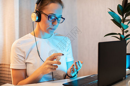 女人对电话表面进行消毒病菌卫生液体电脑笔记本商务互联网面具消毒剂员工图片