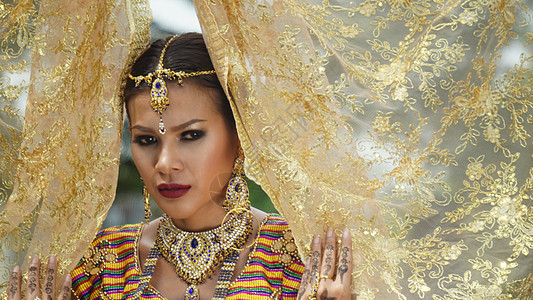 年轻新娘的肖像 穿着婚礼Hijab站在户外化妆品指甲花眼睛珠宝衣服文化戏服女性女孩传统图片