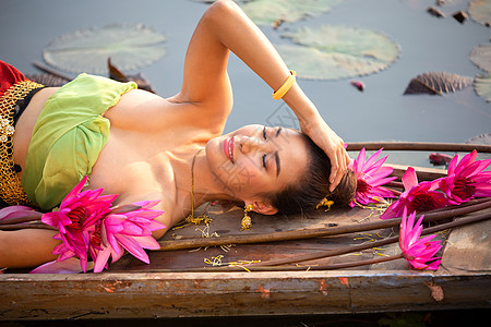 佛教莲花身着传统服饰的年轻亚洲女性在船上和池塘里的粉红色莲花 穿着传统服装的漂亮女孩 泰国语 大城府 优雅微笑裙子古董装饰品宗教文化女孩背景