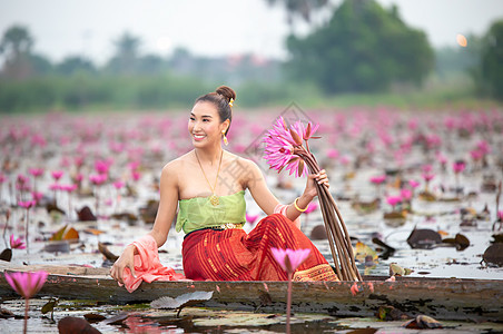 身着传统服饰的年轻亚洲女性在船上和池塘里的粉红色莲花 穿着传统服装的漂亮女孩 泰国语 大城府 优雅宗教戏服节日微笑裙子舞蹈家旅行图片