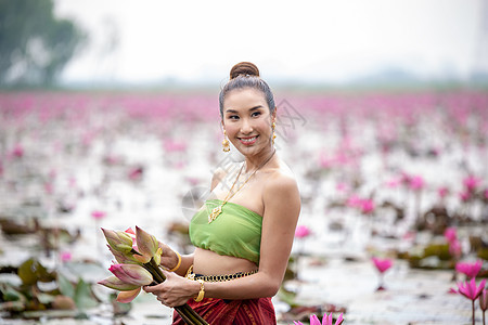 佛教莲花身着传统服饰的年轻亚洲女性在船上和池塘里的粉红色莲花 穿着传统服装的漂亮女孩 泰国语 大城府 优雅旅行女士女孩历史节日文化丝绸艺背景