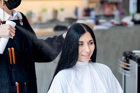 白种女人用美容院理发师喷洒毛发产品 她在店里微笑着放松和快乐的情绪图片