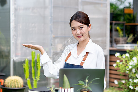 美丽的亚洲女孩举起手 看起来像礼物 看着相机 可持续的小型企业工作涉及植物群概念图片