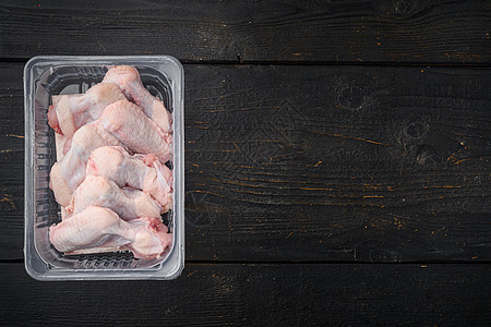 塑料袋中的原鸡翅 黑色木制桌底的黑木板背景 顶角平面 有文字复制空间黑木翅膀包装塑料产品家禽白色食物真空图片