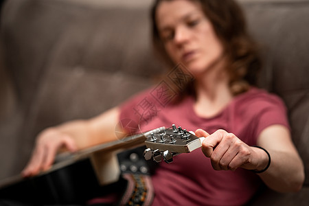 在沙发上在家里弹吉他的女人歌曲女士艺术细绳女性乐趣吉他手女孩乐器音乐家图片