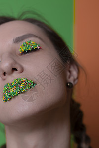 年轻女子肖像 配有糖果化妆品  多彩的糕点 在嘴唇和眼皮上贴珍珠 绿色和橙色的背景 复活节主题口红选择性焦点女孩食物橙子图片