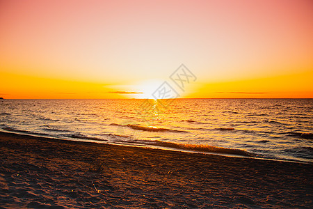 海上日落 海面上温暖的阳光明媚的日落 海浪 太阳落在地平线上场景季节晴天魔法天空反射海景天气海滩橙子图片